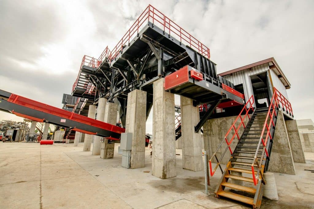 Metro Recycling's processing facility with elevated conveyors, concrete supports, steel staircases, and safety railings.