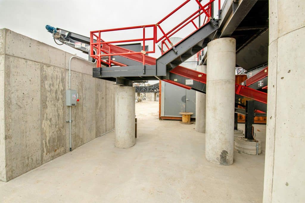 Metro Recycling's processing plant with concrete walls, steel staircases, red railings, and conveyor systems.